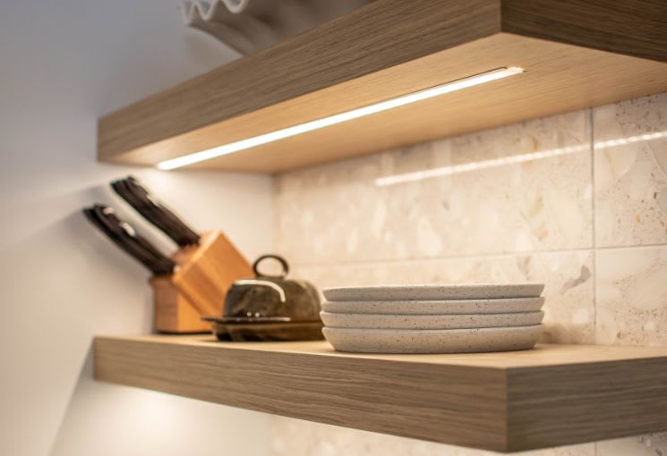 Close up of light strip under wooden floating shelf 