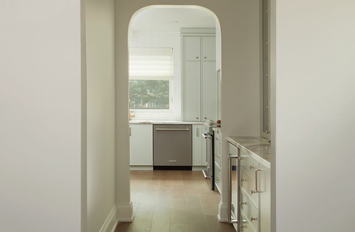 archway door frame into modern kitchen with white custom cabinets