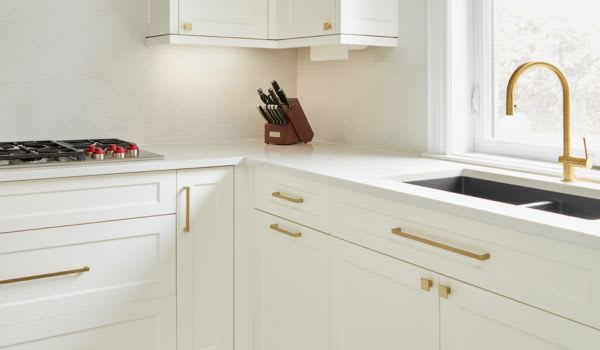 Corner of a custom white kitchen with gold hardware