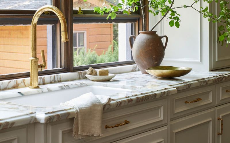 Close up of marble sink with detailed white kitchen cabinets