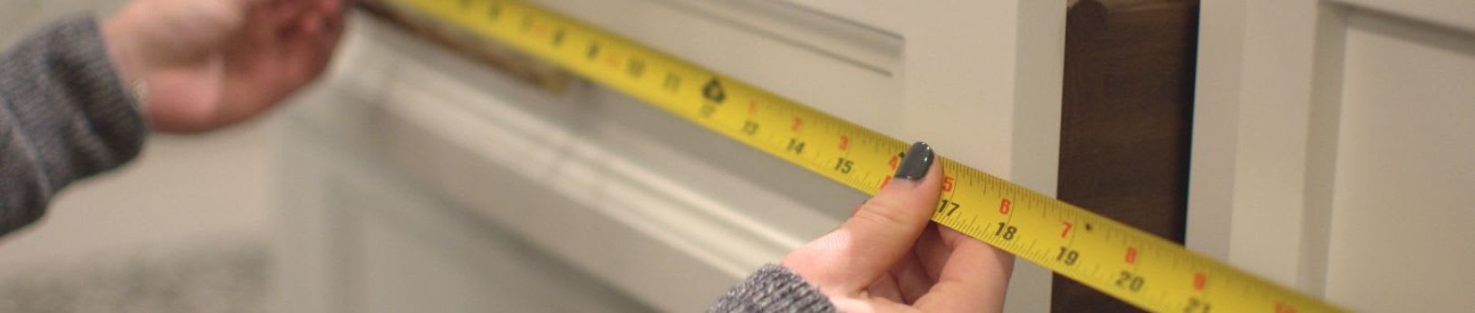 Close up of measuring tape against white cabinets