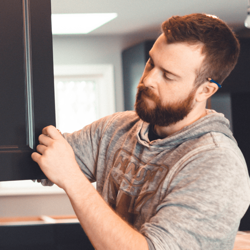 cabinet installer working on installing hardware in black kitchen